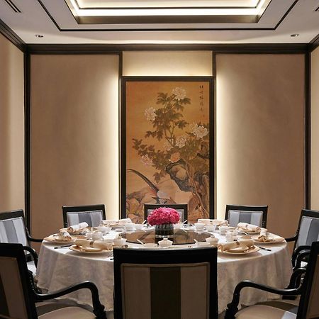 מלון Jw Marriott קואלה לומפור מראה חיצוני תמונה The photo shows an elegant dining room setup featuring a round table covered with a white tablecloth. The table is arranged with several place settings, including plates, cups, and a decorative centerpiece with flowers. The walls are adorned with a t