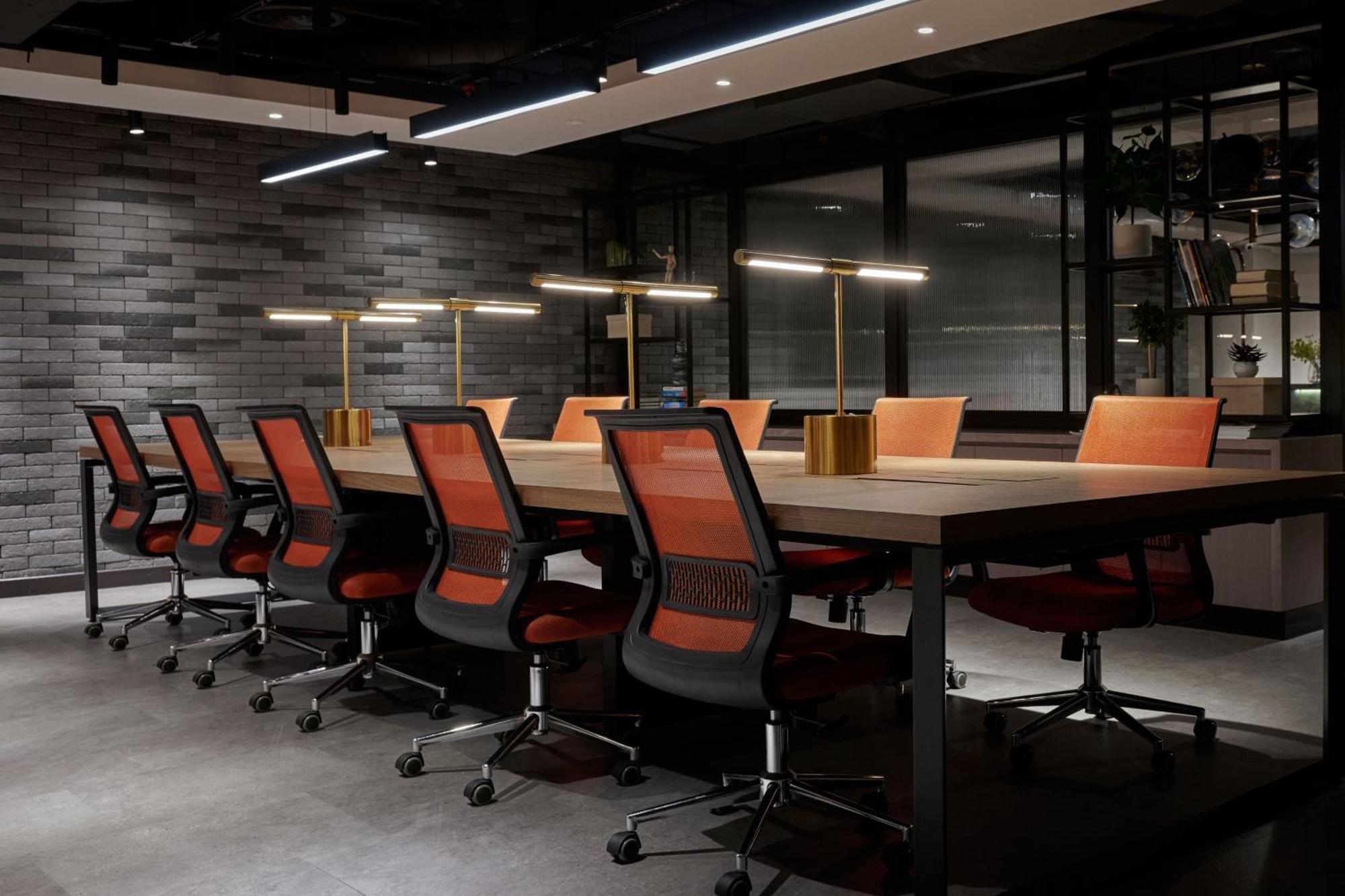 מלון Jw Marriott קואלה לומפור מראה חיצוני תמונה The photo shows a modern conference room featuring a long wooden table surrounded by several black ergonomic chairs with orange accents. Above the table, there are stylish lamp fixtures providing warm lighting. The room has a contemporary design with