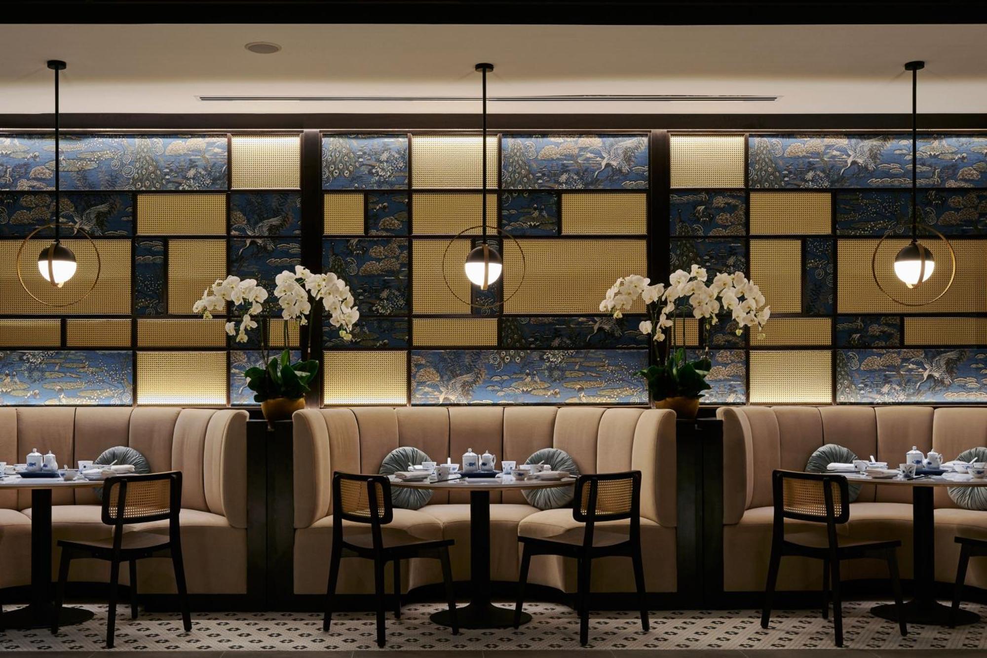 מלון Jw Marriott קואלה לומפור מראה חיצוני תמונה The photo shows an elegant restaurant interior. The design features a stylish, modern aesthetic with tufted beige banquettes along the walls and dark wooden chairs. There are small round tables set with dishes and blue-and-white tableware. The backdr