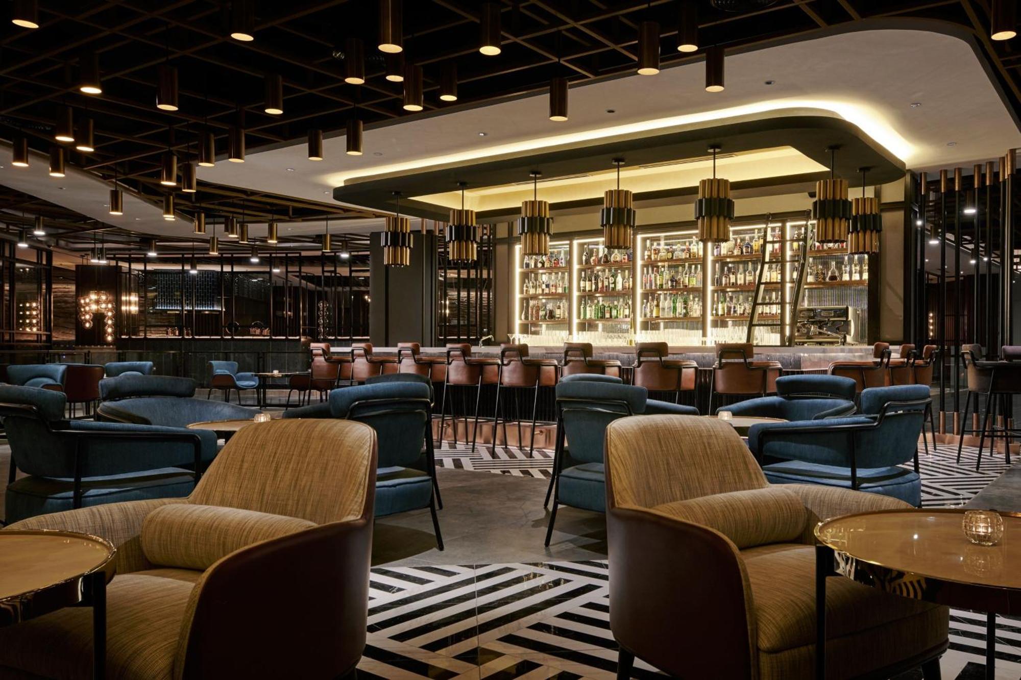 מלון Jw Marriott קואלה לומפור מראה חיצוני תמונה The photo depicts an elegant bar or lounge area inside a modern restaurant. The space features a stylish design with a combination of seating options, including plush armchairs and bar stools. The bar is well-stocked with a variety of bottles display